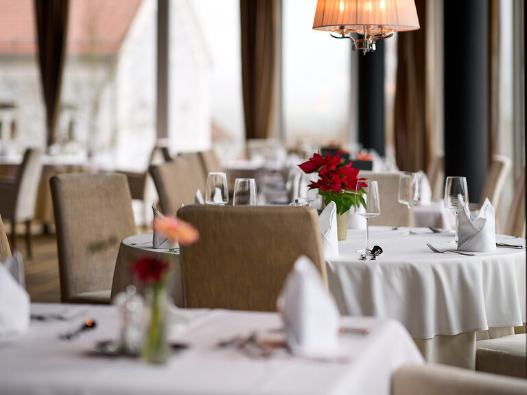 Elegant gedeckte Tische im Restaurant vom Hotel Oswald mit stilvoller Beleuchtung für eine gemütliche Atmosphäre.