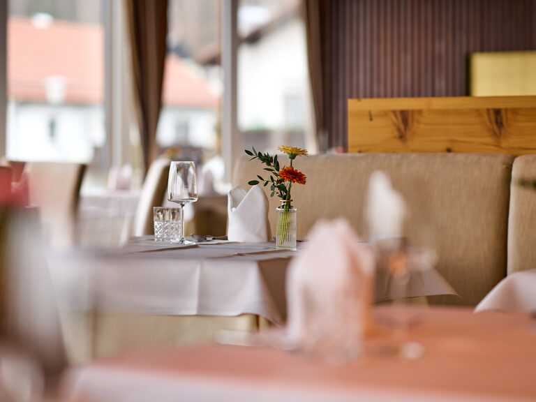 Gedeckter Tisch im Restaurant Galerie im Hotel Oswald mit frischen Blumen.